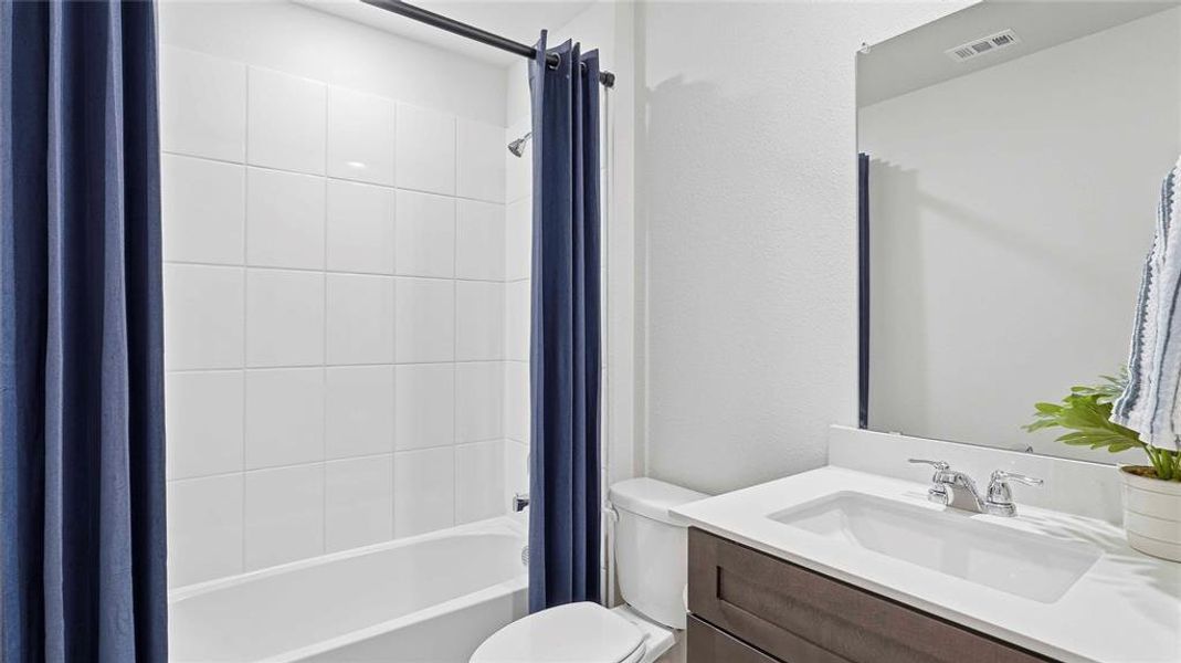 Bathroom featuring vanity and shower / bath combination with curtain