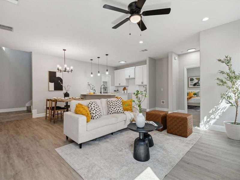 Living room featuring ceiling fan with notable chandelier, sink, and light hardwood / wood-style flooring