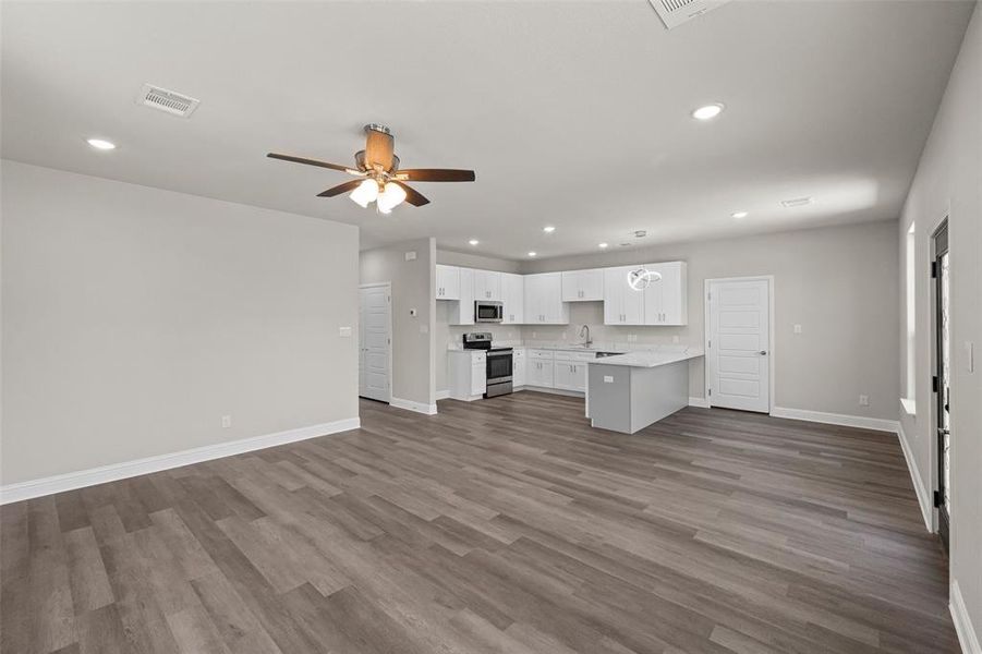 Unfurnished living room with hardwood / wood-style flooring, sink, and ceiling fan