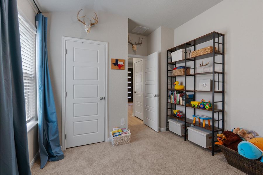 Wall-to-wall carpeting with a neutral tone, white five-panel interior doors, light gray wall paint, and a window with horizontal blinds Wall-to-wall carpeting with a neutral tone, white five-panel interior doors, light gray wall paint, and a window with horizontal blinds