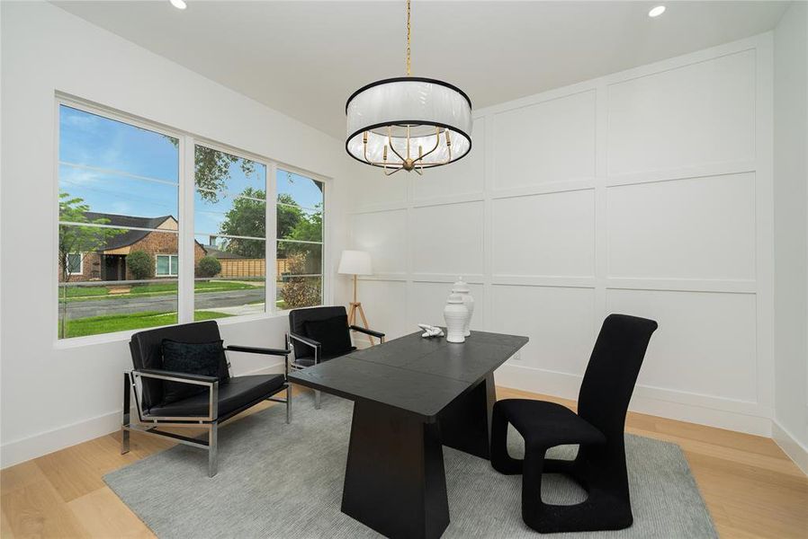 This inviting room features large windows, light wood flooring, and a modern chandelier
