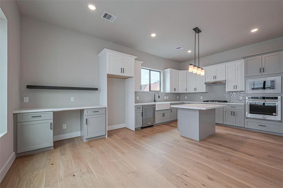 Discover a bright, modern kitchen featuring sleek white cabinets, stainless steel appliances, and a central island. The open layout with light hardwood floors and recessed lighting creates an inviting atmosphere.