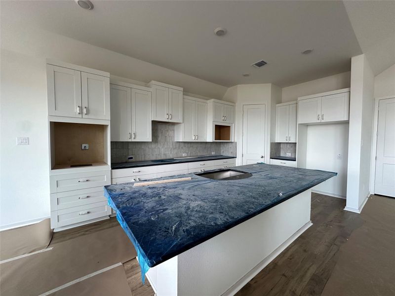 A contemporary kitchen showcasing a spacious island with a sink and ample cabinetry, ready for culinary endeavors.