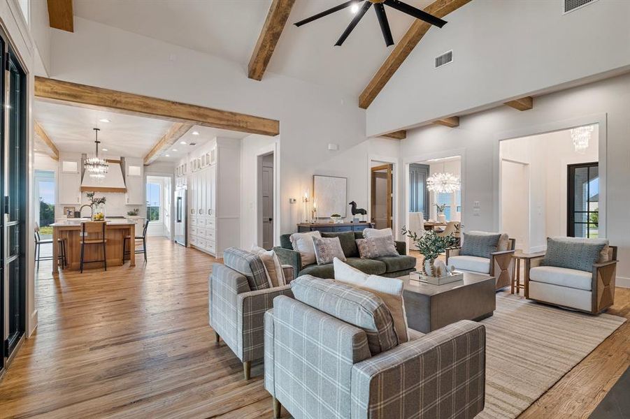 Living room featuring light hardwood / wood-style floors, ceiling fan with notable chandelier, beamed ceiling, high vaulted ceiling, and sink