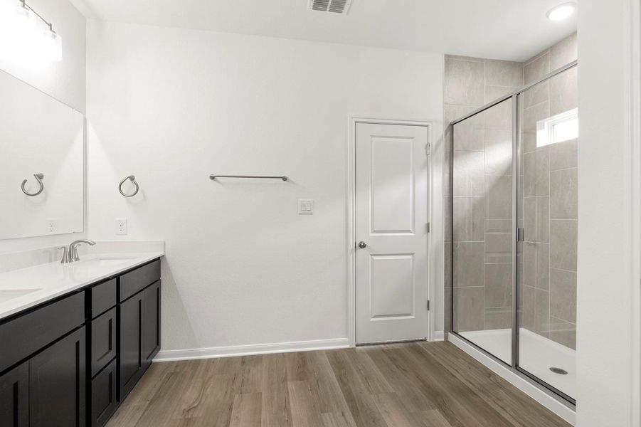 Bathroom featuring a stall shower, double vanity, and light wood-style floors