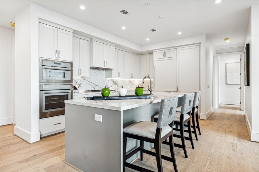 Alternate view of the kitchen with abundant storage space, Thermador appliances, wine chiller and Sub-zero refrigerator with two freezer drawers. Photos are of a similar unit with the same floor plan