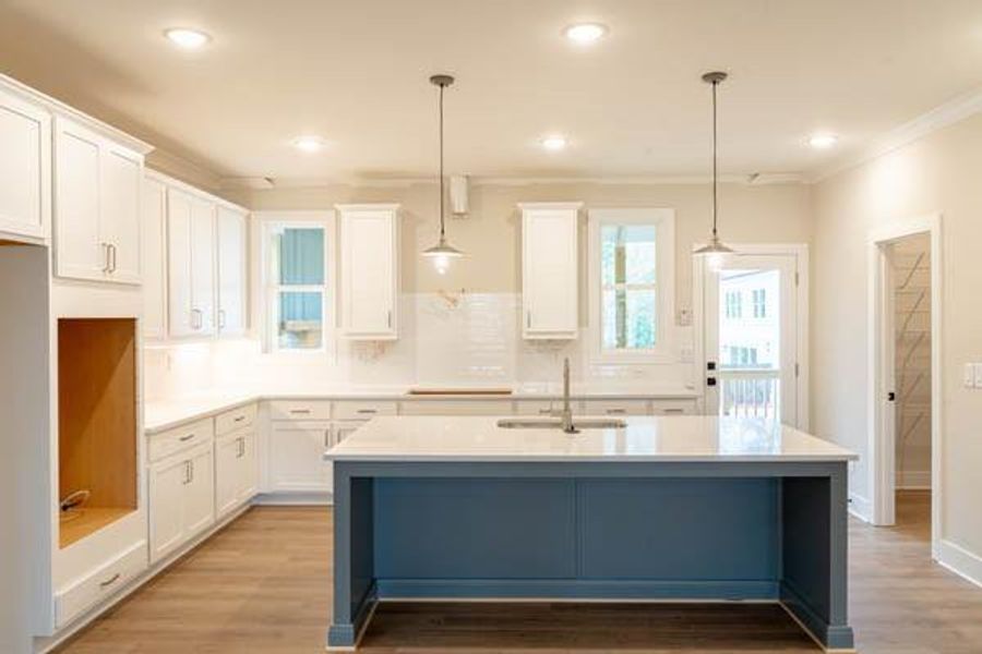 Kitchen featuring hanging light fixtures, a center island with sink, sink, and light hardwood / wood-style flooring Kitchen featuring hanging light fixtures, a center island with sink, sink, and light hardwood / wood-style flooring