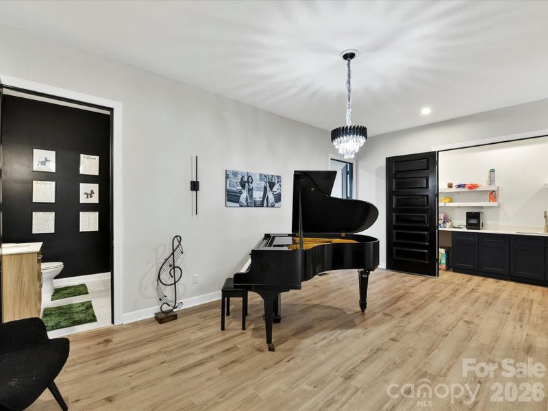 Elegant music room featuring a grand piano, modern lighting, and a spacious layout perfect for entertaining or creative expression.