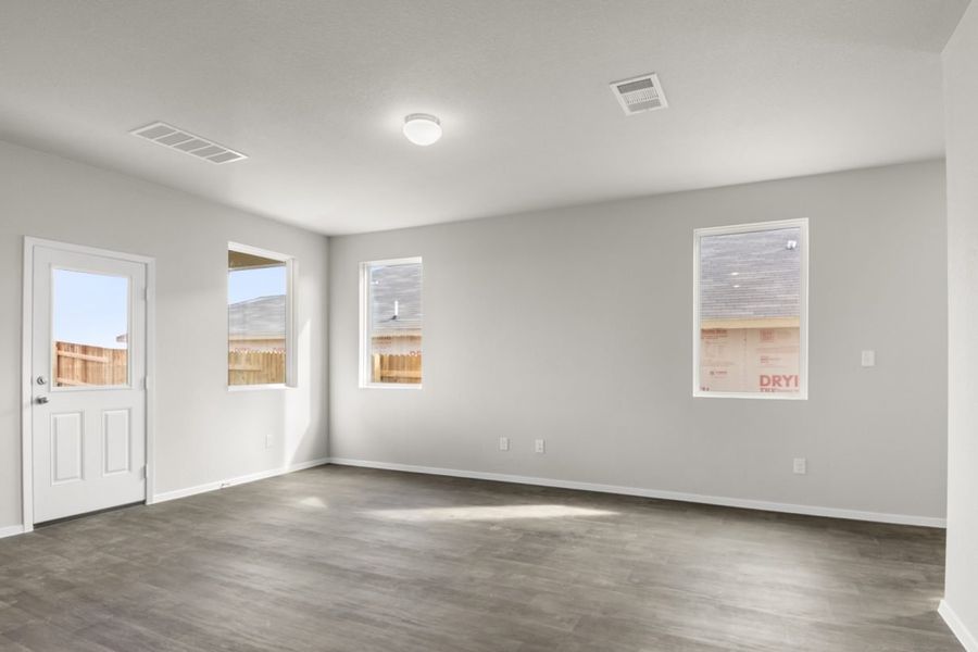 Image of a living room with light grey walls, dark brown flooring, windows and white trim