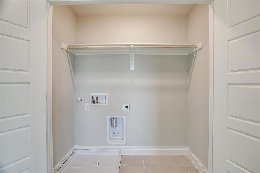 Clothes washing area featuring electric dryer hookup, washer hookup, light tile patterned floors, and gas dryer hookup