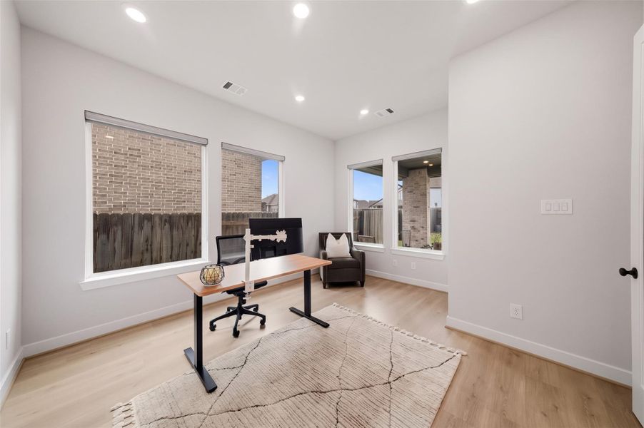 The study offers a refined setting with rich luxury vinyl planked floors, expansive windows with sleek roller shades and elegant 8-foot French doors that create a distinguished entrance. Recessed lighting adds a warm, sophisticated glow, making this versatile space equally suited for a private home office, library or quiet retreat.