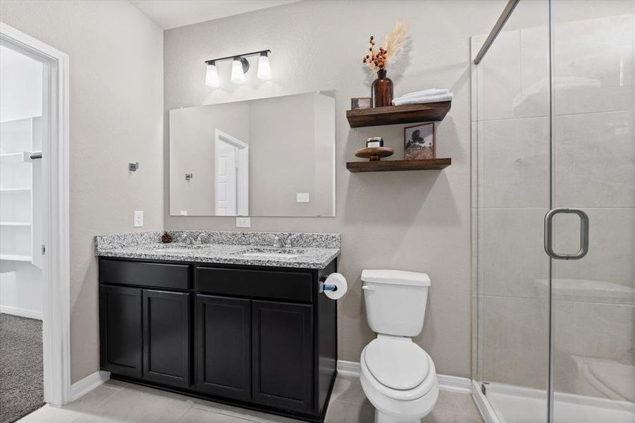 Bathroom featuring double vanity, a stall shower, light tile patterned flooring, and a walk in closet Bathroom featuring double vanity, a stall shower, light tile patterned flooring, and a walk in closet