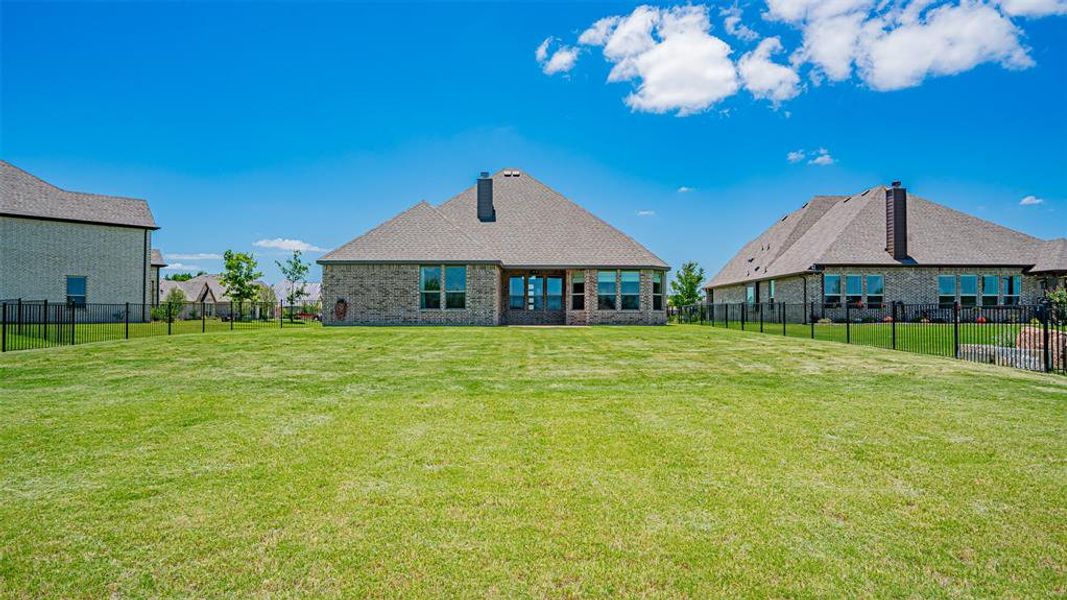Expansive green lawn with a black metal fence enclosing the property