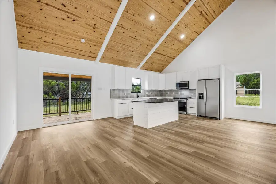 A spacious, open-concept kitchen and living area featuring high vaulted ceilings and a private deck. A spacious, open-concept kitchen and living area featuring high vaulted ceilings and a private deck.