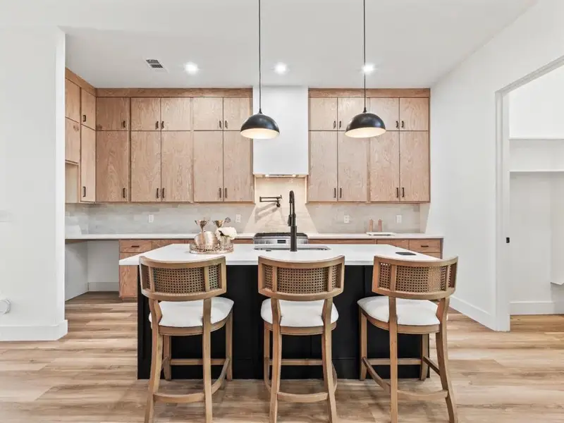 Kitchen with decorative light fixtures, tasteful backsplash, light wood-style flooring, and a breakfast bar area