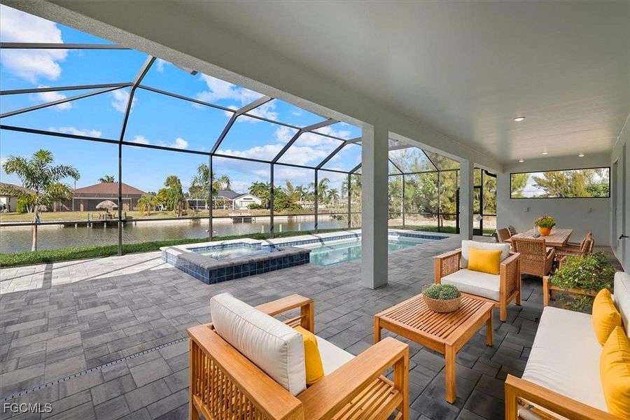 View of patio featuring a lanai, a sunroom, a pool with connected hot tub, and a water view