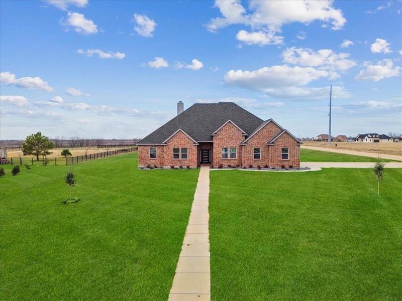 View of front of home featuring fence, a chimney, brick siding, a front lawn, and roof with shingles