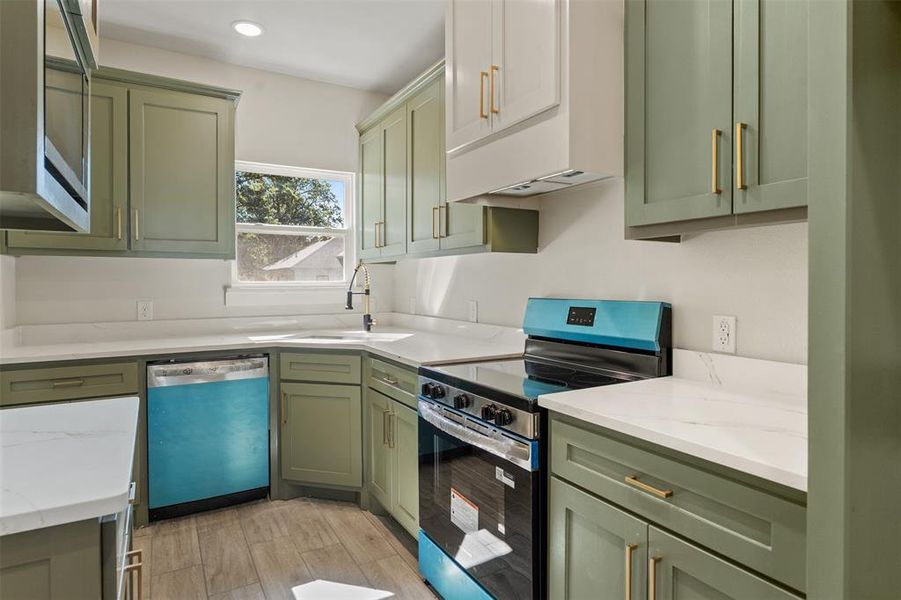 Kitchen featuring sage cabinetry, white countertops, stainless steel appliances, and wood-finish flooring Kitchen featuring sage cabinetry, white countertops, stainless steel appliances, and wood-finish flooring