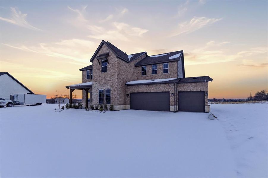 View of front of house with brick siding, an attached garage, and a porch