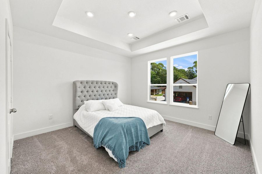Another view of the primary suite showcasing the impressive tray ceiling, generous proportions and bright, airy atmosphere. Another view of the primary suite showcasing the impressive tray ceiling, generous proportions and bright, airy atmosphere.