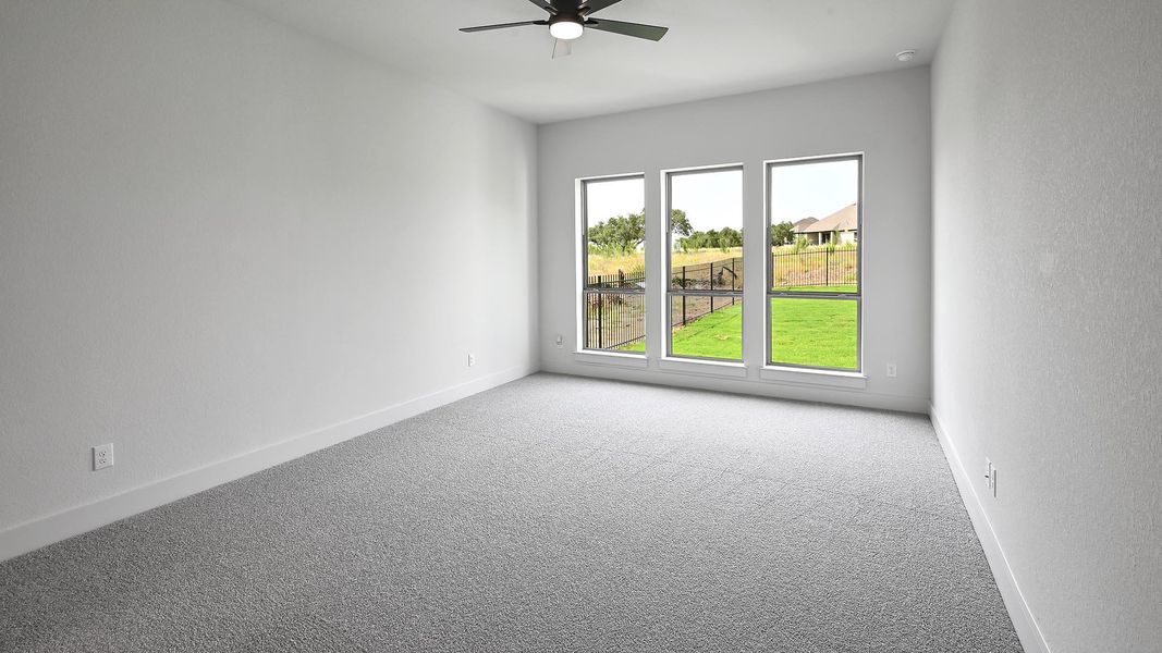 Carpeted spare room with ceiling fan and baseboards