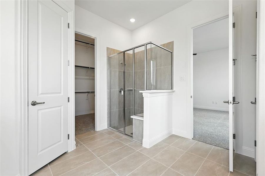 Full bathroom with light tile patterned flooring, a shower stall, and a spacious closet