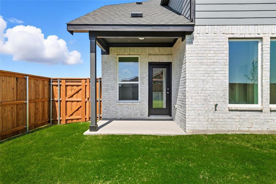 Property entrance with a patio, a gate, brick siding, and a shingled roof Property entrance with a patio, a gate, brick siding, and a shingled roof
