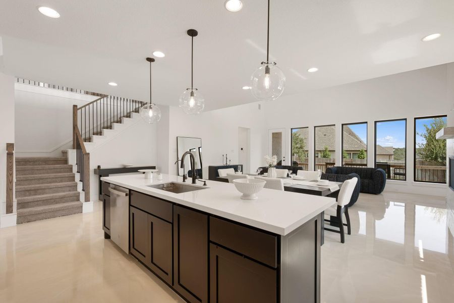 An open-concept living area with abundant natural light features a modern kitchen island and a sleek staircase. An open-concept living area with abundant natural light features a modern kitchen island and a sleek staircase.