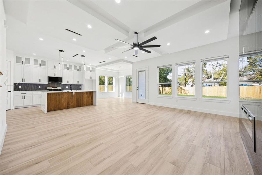 Unfurnished living room featuring beamed ceiling, light wood-style flooring, recessed lighting, and ceiling fan
