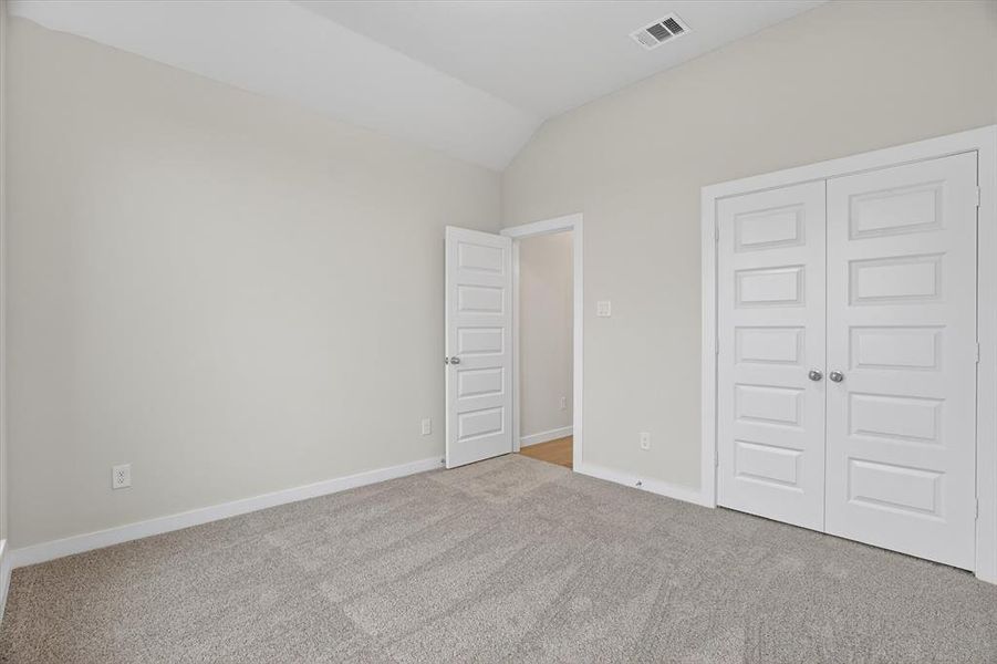 Carpeted room featuring a vaulted ceiling, light neutral wall paint, white trim, and white paneled doors