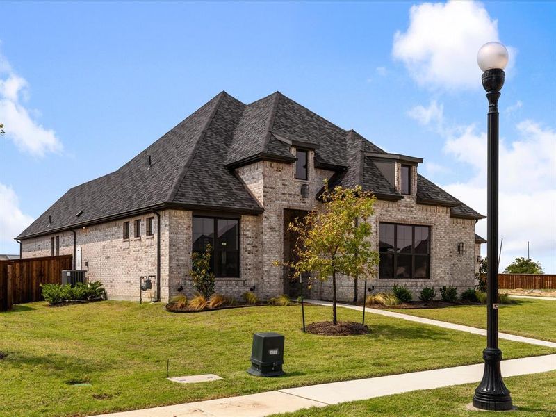 French country home featuring brick siding and a shingled roof French country home featuring brick siding and a shingled roof