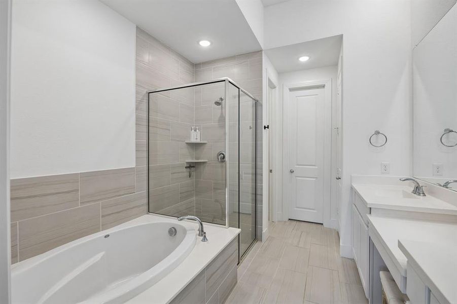Modern bathroom featuring a soaking tub, glass-enclosed shower, dual vanity with undermount sinks, and light-toned tile flooring