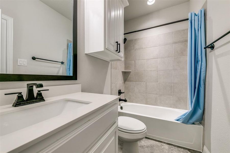 Full bathroom with tile flooring, oversized vanity, toilet, and shower / tub combo