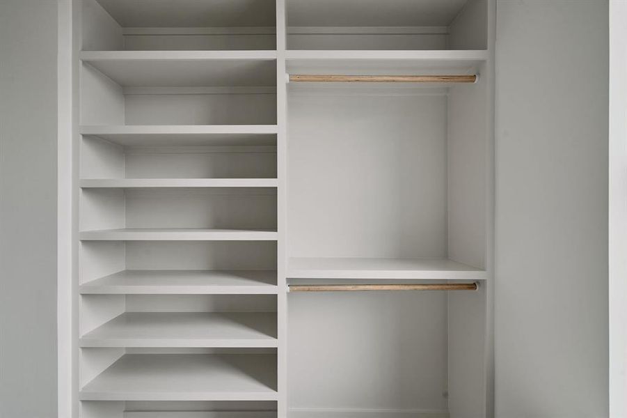 Built-in closet system featuring multiple shelving units, two hanging rods, and a neutral white finish Built-in closet system featuring multiple shelving units, two hanging rods, and a neutral white finish