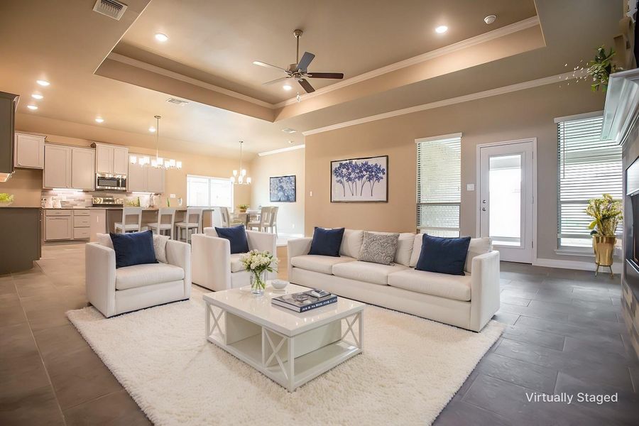 Living area with visible vents, crown molding, ceiling fan with notable chandelier, and a tray ceiling