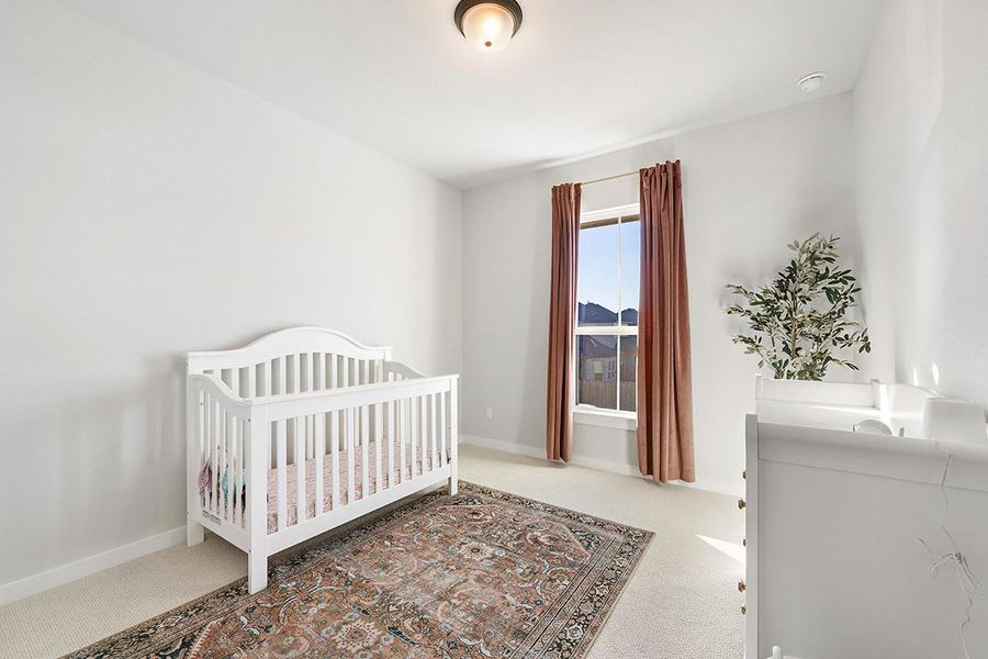Natural light streams through a tall window in this cozy bedroom with plush carpeting.