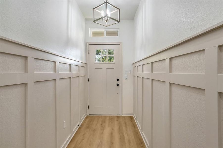 Doorway to outside featuring light hardwood / wood-style flooring and an inviting chandelier