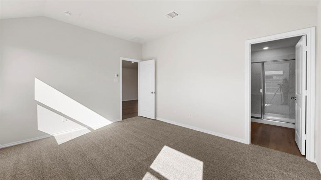 Unfurnished bedroom with dark colored carpet and ensuite bath