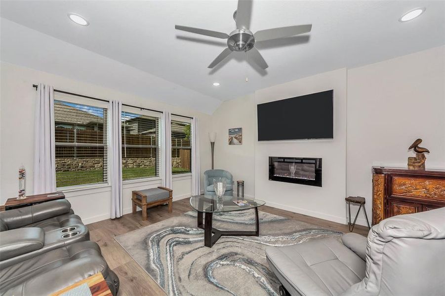 Living room with light hardwood / wood-style flooring, vaulted ceiling, and ceiling fan