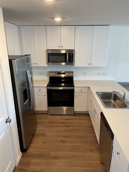 Kitchen featuring appliances with stainless steel finishes, white cabinetry, and light countertops