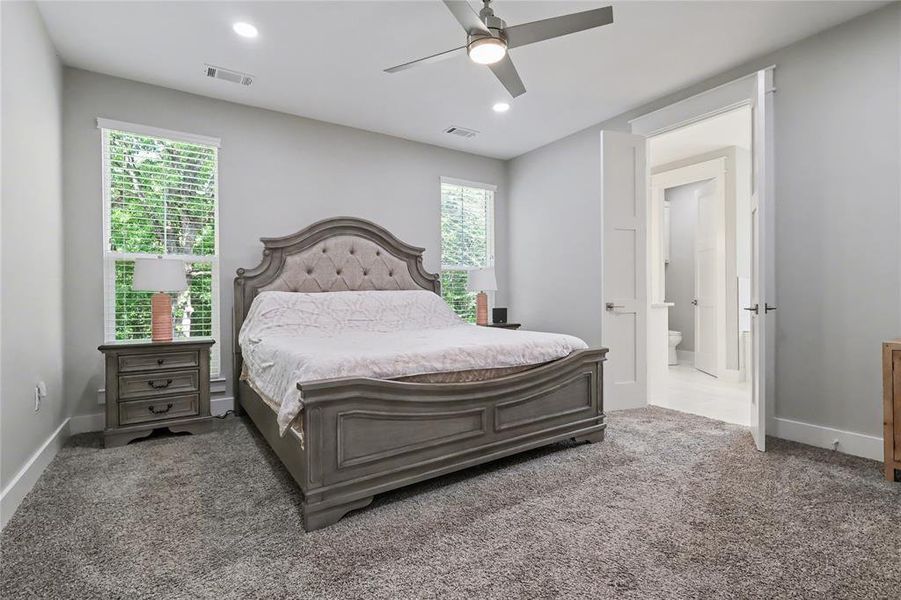 Spacious carpeted room featuring two large windows with blinds, recessed lighting, and a ceiling fan