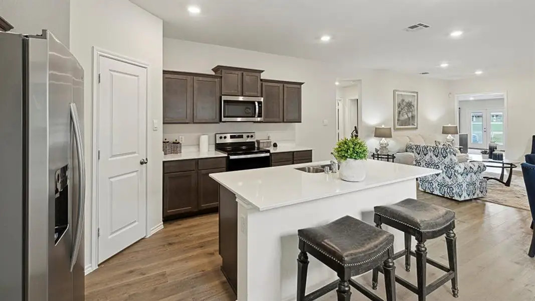 Kitchen with stainless steel appliances, open floor plan, dark wood-style flooring, a kitchen island with sink, and a breakfast bar area Kitchen with stainless steel appliances, open floor plan, dark wood-style flooring, a kitchen island with sink, and a breakfast bar area