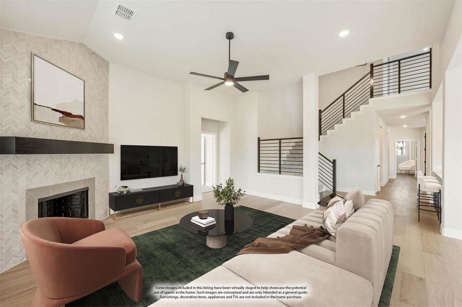 Open living room with tile fireplace, high ceilings, ceiling fan, and staircase with metal railing