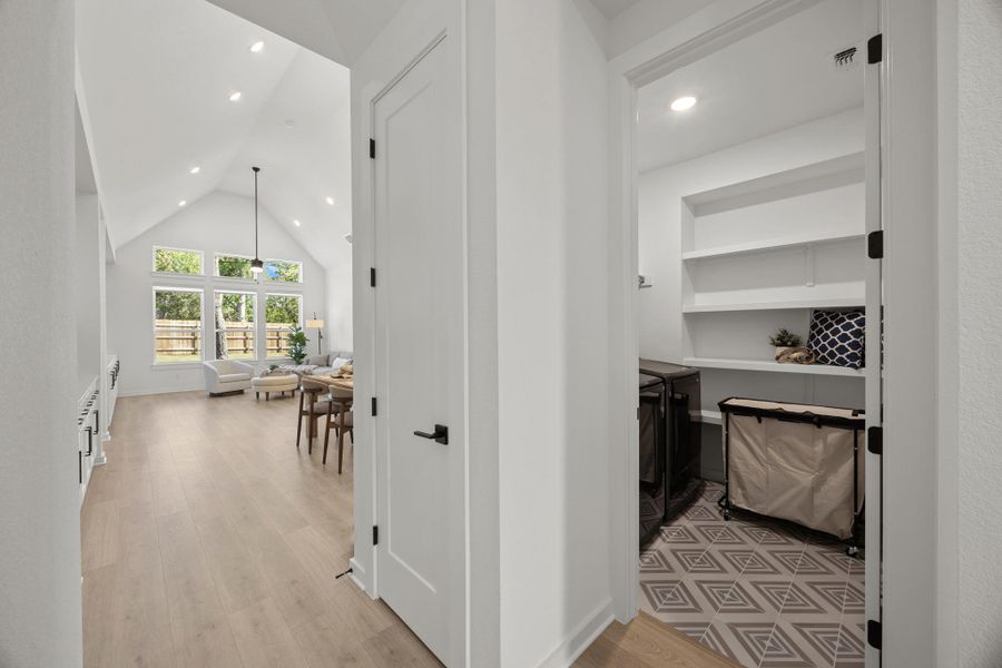 Hallway with recessed lighting, light wood finished floors, washing machine and clothes dryer, and a high ceiling