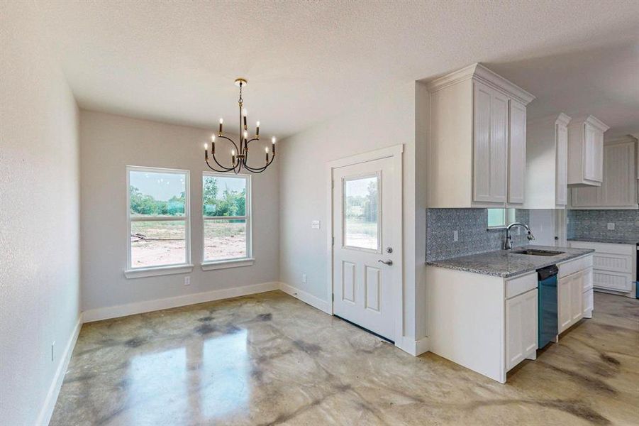 Kitchen with tasteful backsplash, an inviting chandelier, sink, and white cabinets