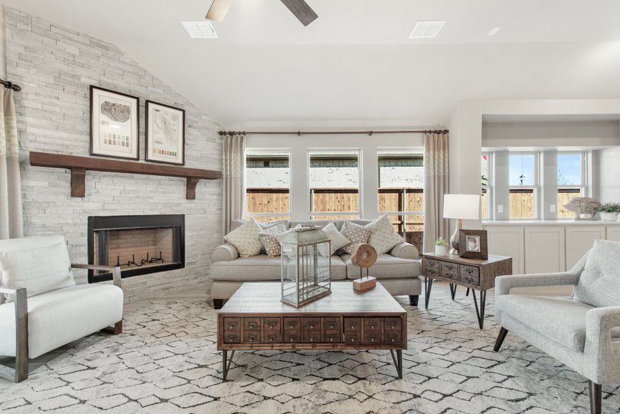 Living room with stone fireplace, vaulted ceiling, neutral furniture, and patterned area rug