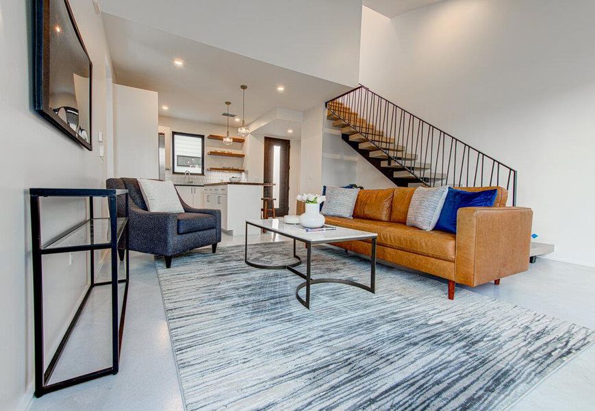 Living room featuring finished concrete floors, recessed lighting, and stairway