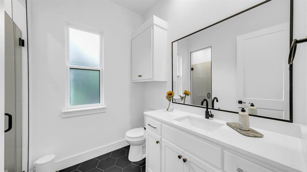 Bathroom featuring toilet, vanity, tile patterned flooring, and a shower stall Bathroom featuring toilet, vanity, tile patterned flooring, and a shower stall