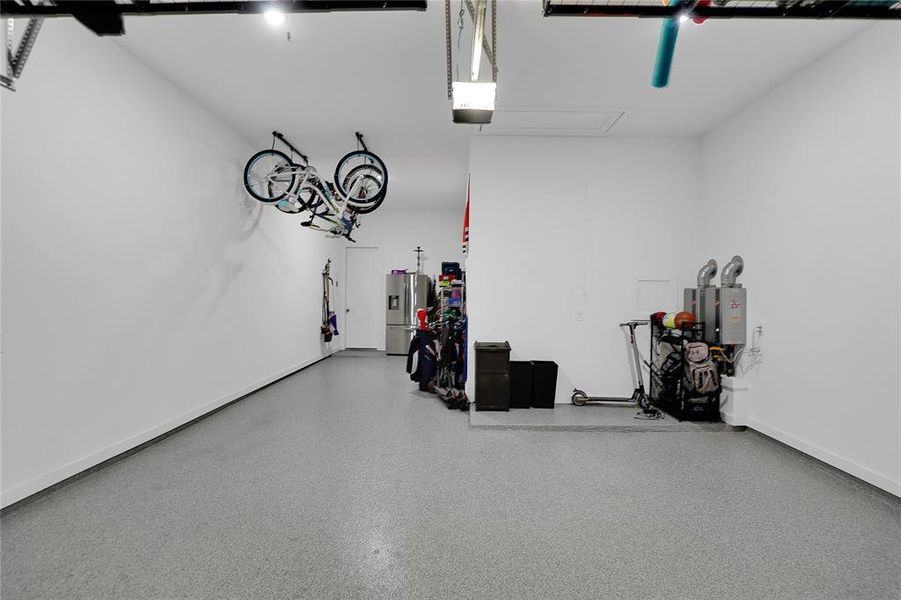 Garage with epoxy flooring, white painted walls, and ceiling-mounted storage racks