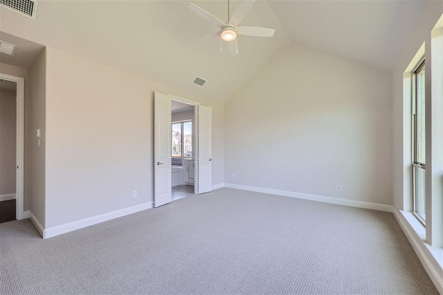 Unfurnished bedroom with carpet floors, ceiling fan, and high vaulted ceiling